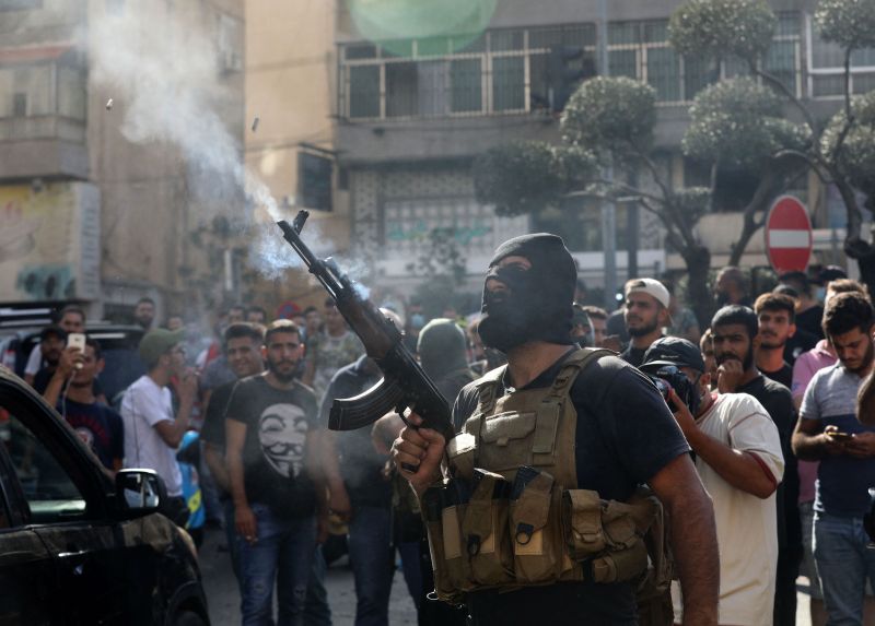 Un miembro del movimiento libanés Hezbolá dispara su arma durante el funeral de algunos de sus miembros que murieron durante los enfrentamientos en el barrio de Tayouneh de los suburbios del sur de la capital, Beirut, un día antes, el 15 de octubre de 2021.