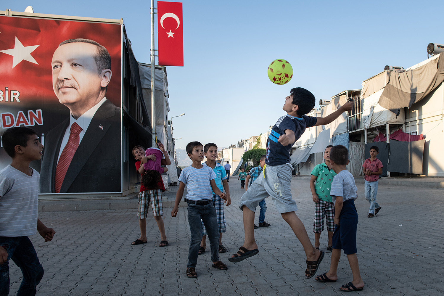 Niños refugiados sirios juegan frente a un cartel del presidente turco Erdogan