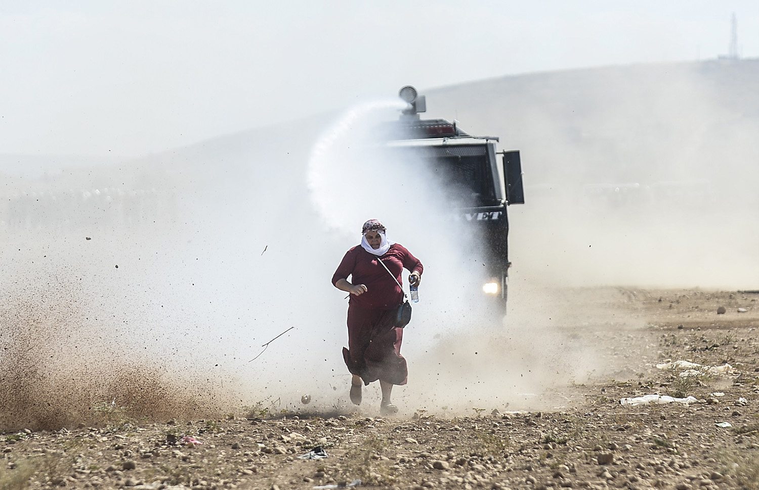 Una mujer kurda huye de un cañón de agua durante los enfrentamientos con soldados turcos cerca de la frontera con Siria.