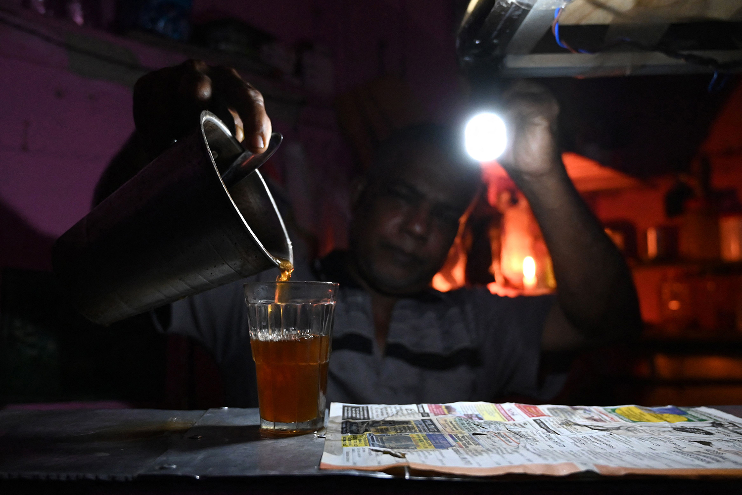 Un vendedor trabaja en su tienda de té durante un apagón en Sri Lanka.