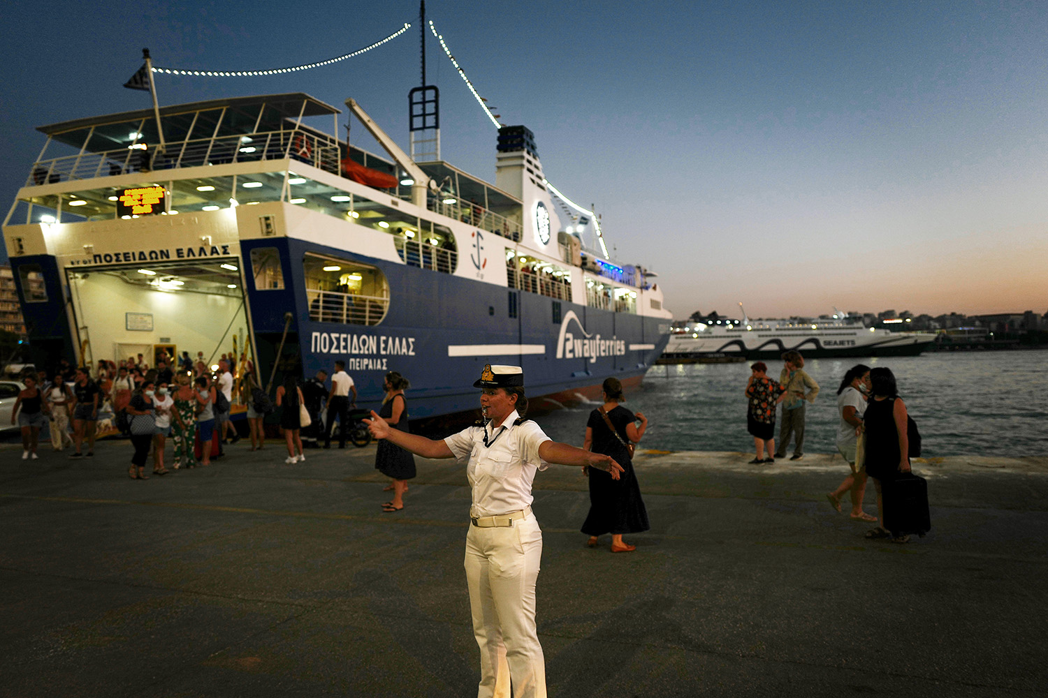Funcionarios portuarios dirigen el tráfico desde un ferry en El Pireo, Grecia.