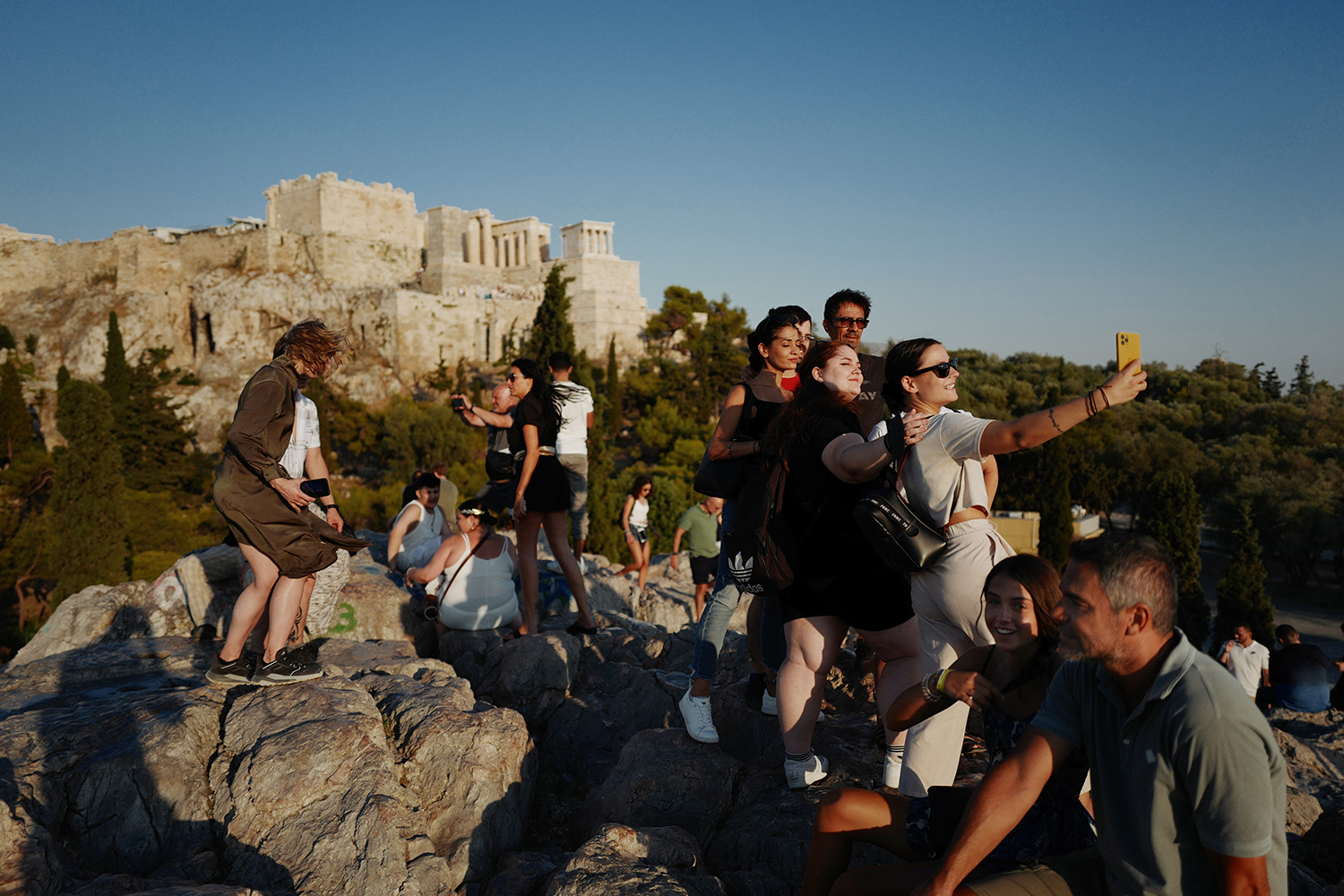 Los turistas posan para hacerse selfies a los pies de la Acrópolis.