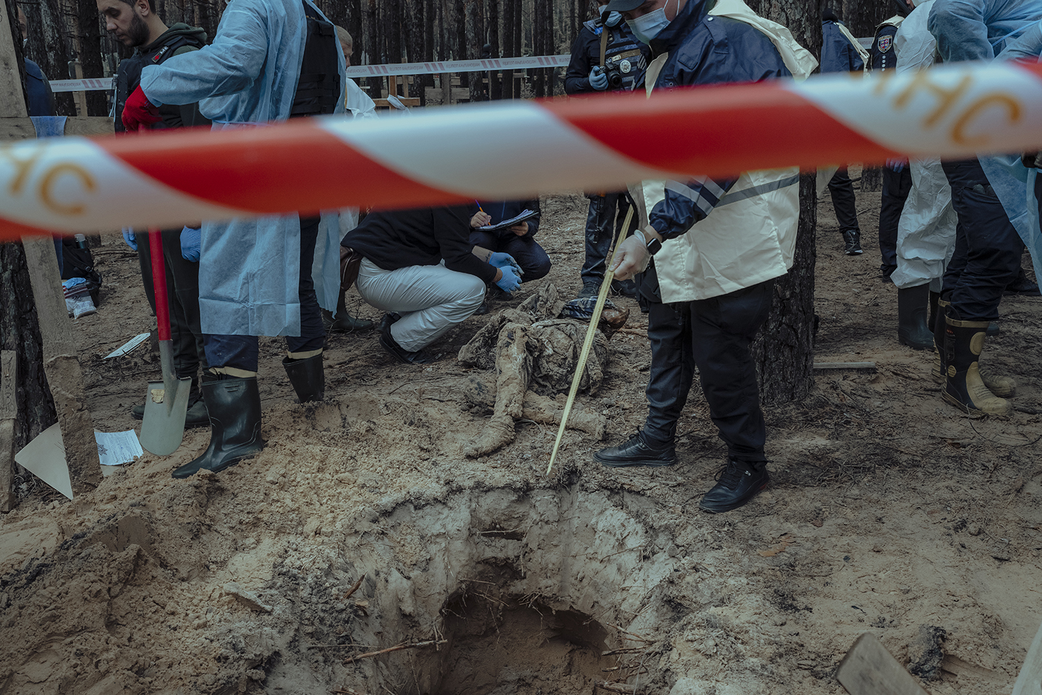Trabajadores ucranianos sacan un cuerpo de una tumba en Izyum.
