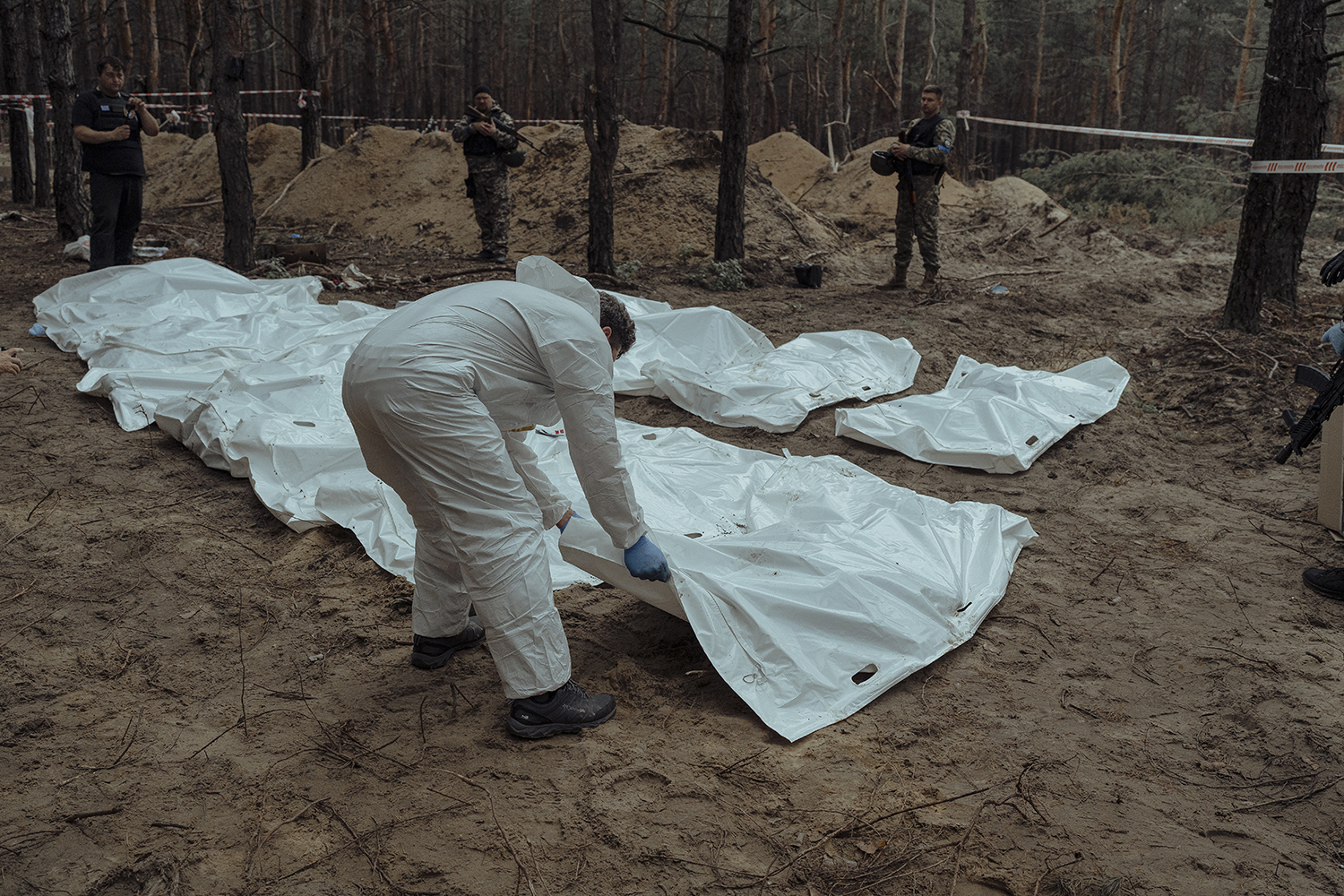 Las bolsas de cadáveres son llevadas a contenedores refrigerados tras la exhumación en Izyum