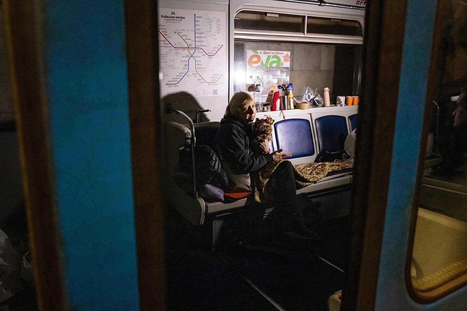 Una mujer se sienta con su perro en un vagón de una estación de metro, que se utiliza como refugio antibombas en Kyiv