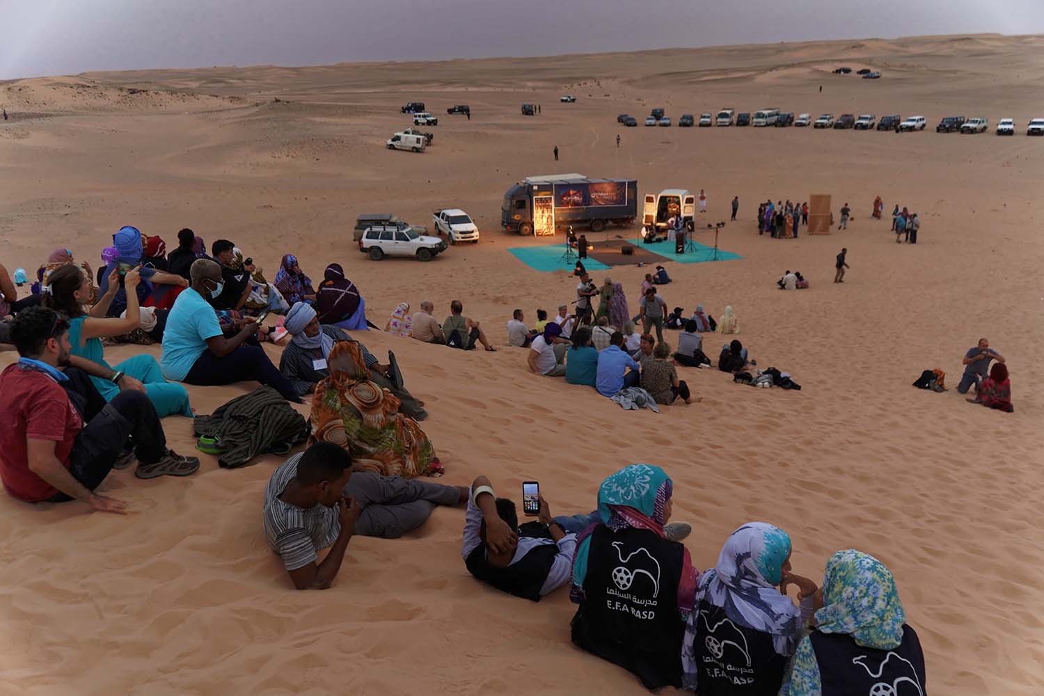 Un público se sienta en una duna de arena a unos 30 minutos en coche del campamento de Auserd para ver un concierto de FiSahara en el Sáhara Occidental.