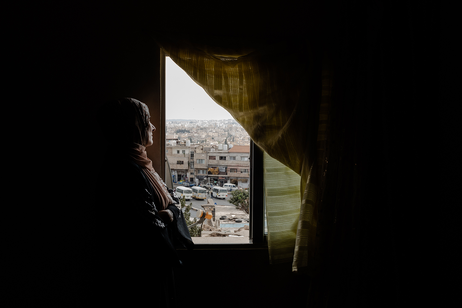 La madre del preso político Anas al-Jamal mira a través de la ventana de su sala de estar.