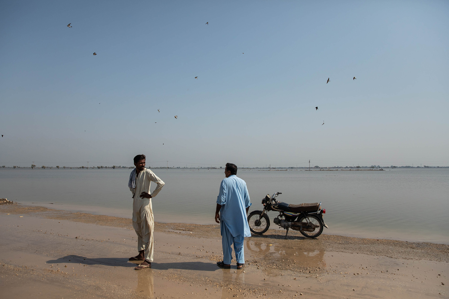 Hombres en la carretera rodeados por las aguas de las inundaciones en Pakistán.