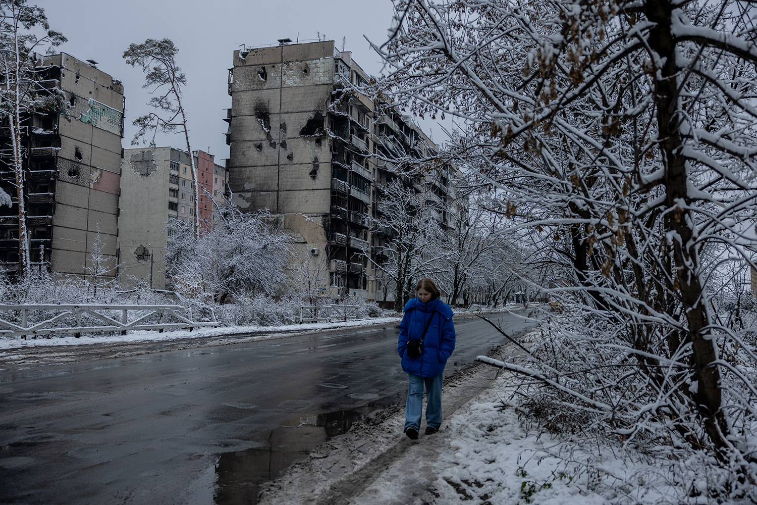 Una mujer camina por las calles cubiertas de aguanieve junto a casas bombardeadas y destruidas en Irpin el 28 de noviembre.