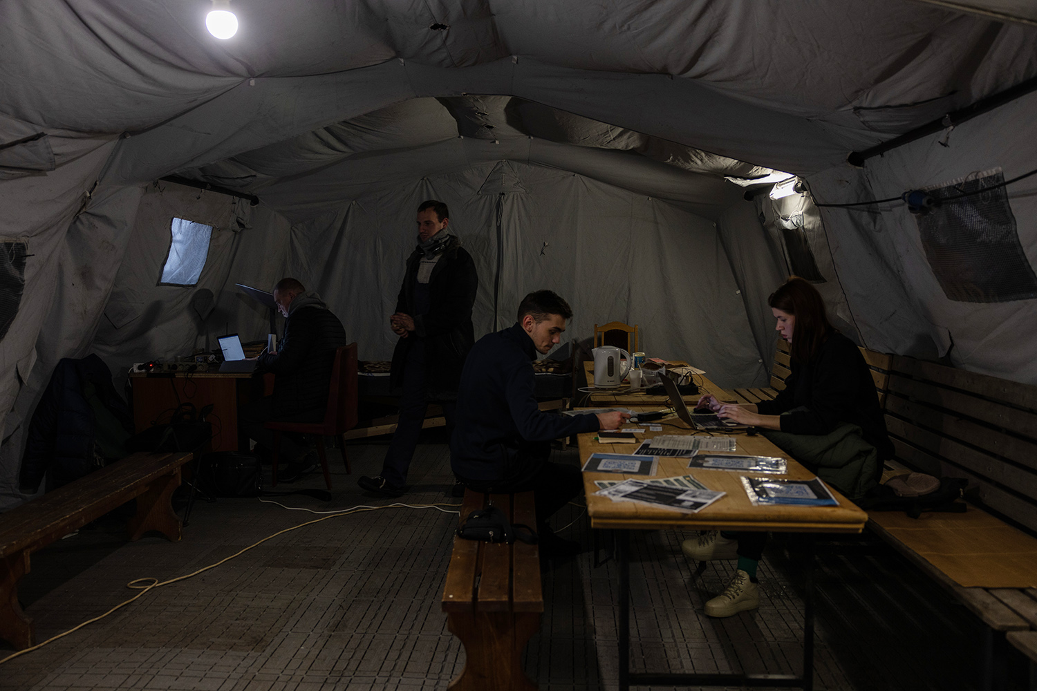 Varias personas se reúnen en tiendas de campaña con calefacción en Kiev el 28 de noviembre. Los refugios temporales están preparados para proporcionar bebidas calientes, electricidad, internet e incluso un lugar donde dormir si es necesario.