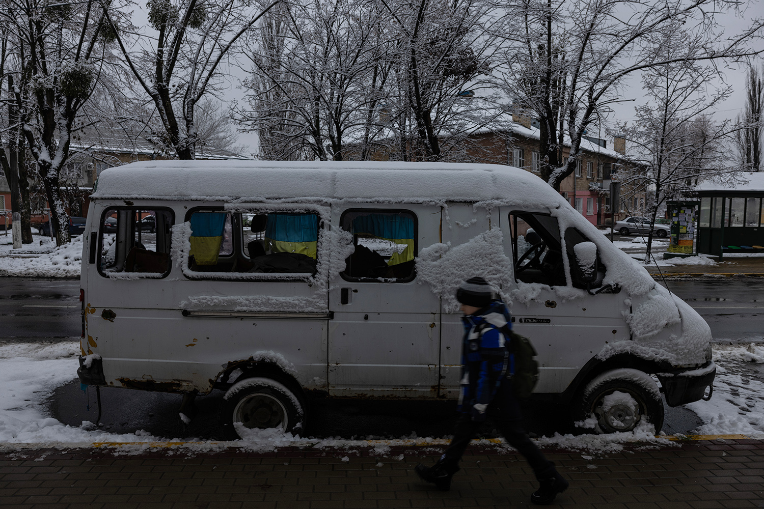 Un niño pasa junto a una furgoneta cubierta de nieve y envuelta en la bandera ucraniana en Irpin el 28 de noviembre.