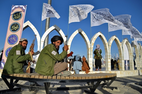 Combatientes talibanes esperan mientras la gente se reúne para una ceremonia para izar la bandera talibán en Kabul.